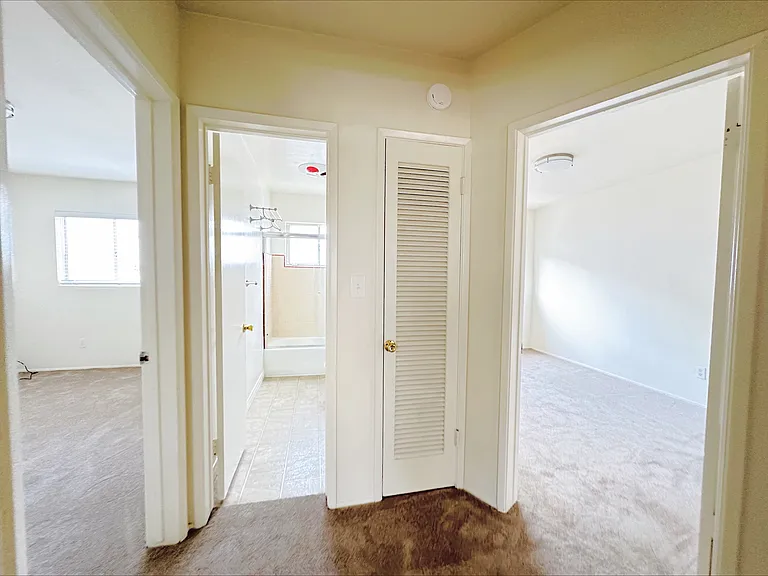 Hallway with 1 bedroom on either side and shared bathroom in the middle. Closet space ahead, and cabinet space in hallway as well!