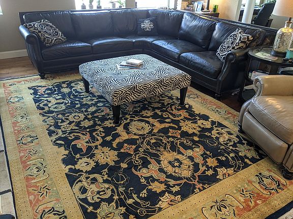 Living room with handtied wool carpet. Square ottoman has been replaced with a round coffee table .