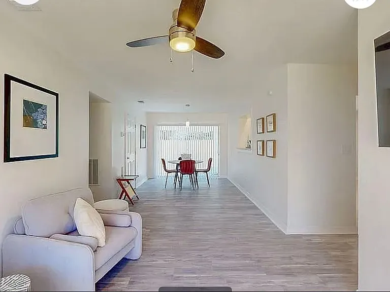Open-concept living and dining area with hardwood-style floors, ceiling fan, and natural light throughout