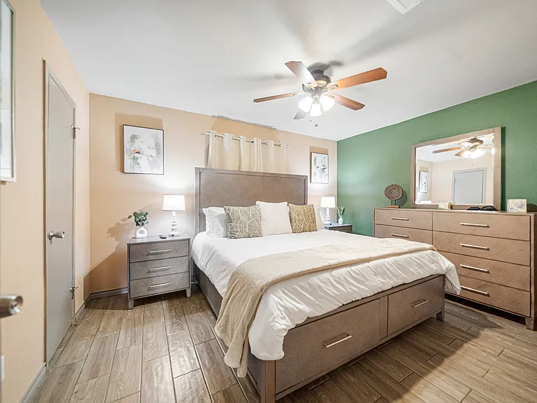 Master bedroom with king size bed, dresser, underbed storage and 32" TV