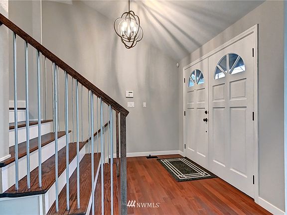 Entry features new custom white oak stairs, New Bellawood 100 year transferable hardwood flooring, modern light fixture.