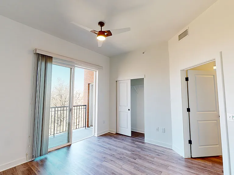 Spacious bedroom with wood-style flooring and balcony.