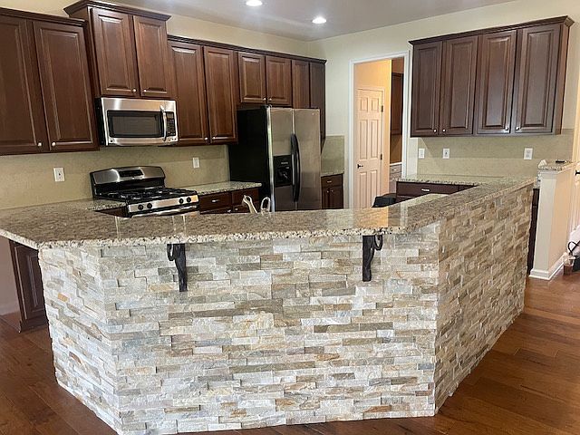 Stacked stone accents this spacious and immaculate kitchen with granite countertops, bar, stainless appliances, and tons of storage. Gas range!