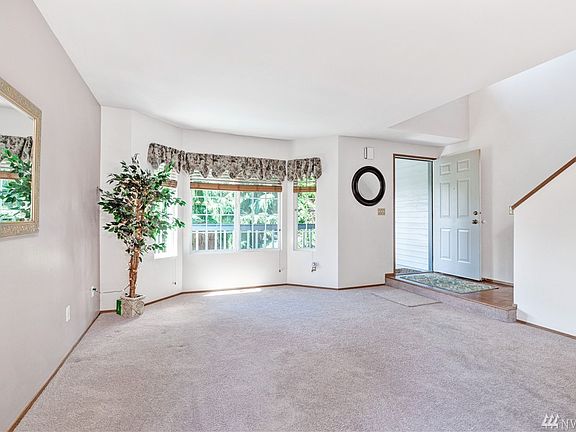 Living room with bright windows, vaulted ceiling in entry and stairway
