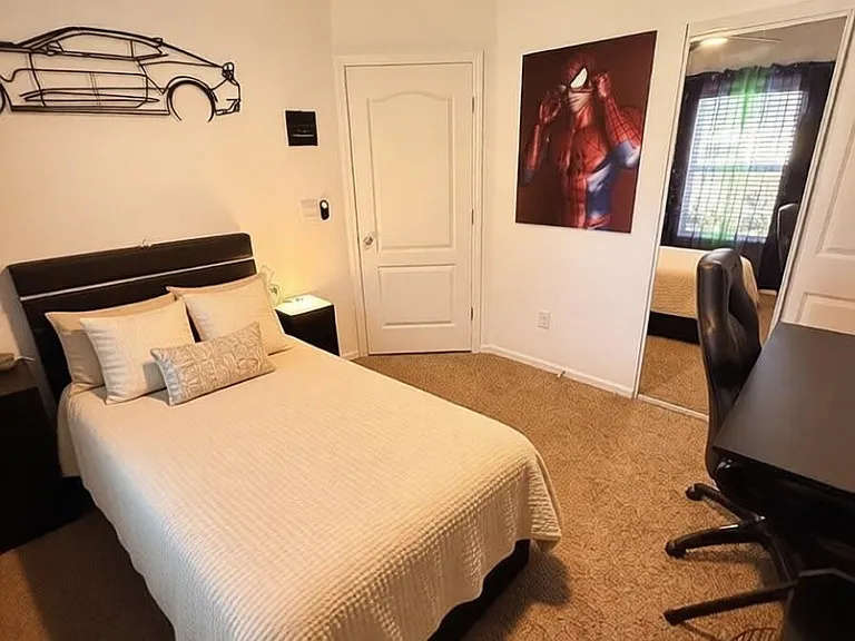 Furnished bedroom with a full bed, ceiling fan, mirrored closet doors, and a desk setup for work or study.