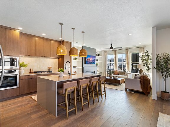Modern open-concept kitchen and living room with wood floors, an island with barstools, pendant ligh