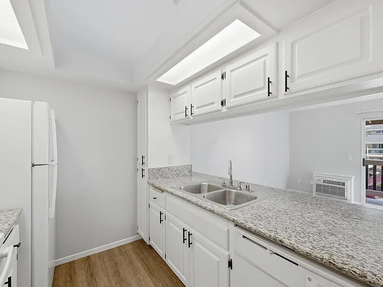 A kitchen with white cabinets and a granite countertop.
