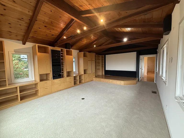 A media room features vaulted ceiling, view windows, a pull-down screen and stage.