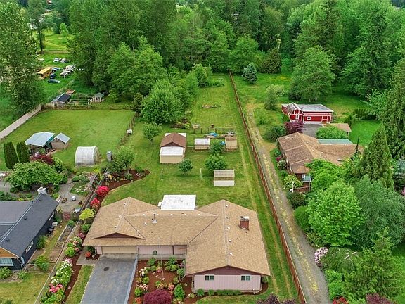 Aerial shot of the fully fenced, shy 1.5 acre lot featuring an orchard & huge blackberry bushes! A perfect mini-farm or home business location or simply enjoy the tranquil setting that feels like your own park. Photo reflects new roof to be installed - detached sun porch roof will also be new