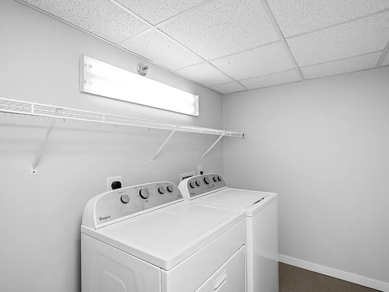 Modern laundry room featuring energy-efficient washer and dryer with ample shelving and bright lighting. Modern laundry room featuring energy-efficient washer and dryer with ample shelving and bright lighting.