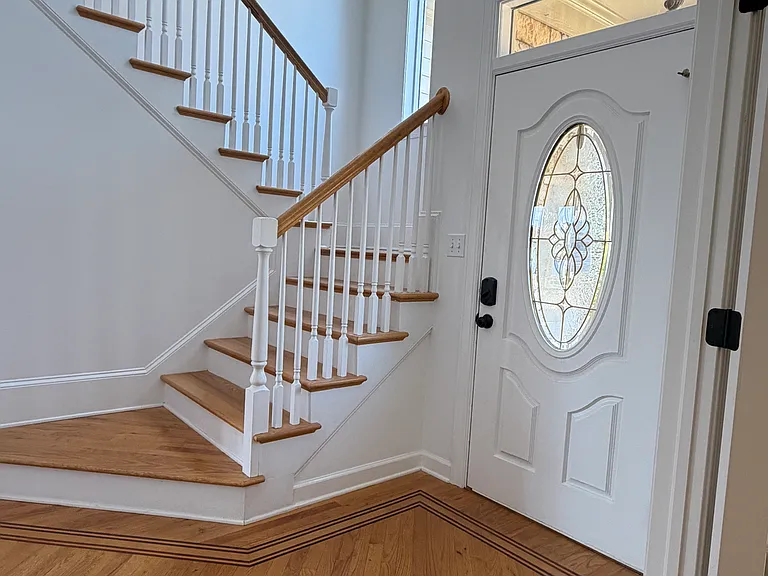 Inviting entryway with hardwood floors, a classic curved staircase and natural light from the arched window _ the perfect first impression for guests.