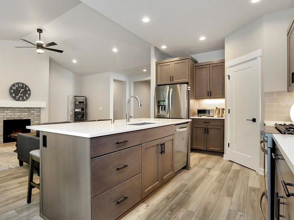 Open concept design - kitchen looks out to living area with vaulted ceiling, fan, cozy fireplace. Easy care vinyl plank flooring throughout kitchen and living area.