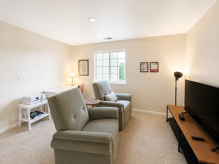 Shared tenant lounge with comfortable reclining chairs, TV, and dedicated workspace.