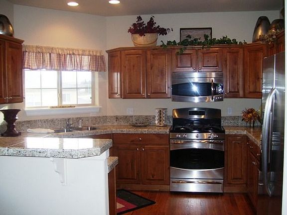 Upgraded kitchen with hardwood, stainless appliances, granite tile countertops