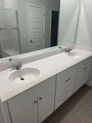 Spacious double-sink vanity with ample cabinet storage, plus a glass-enclosed shower for convenient daily routines.