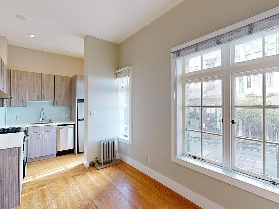 Bright kitchen with modern wood cabinets, countertops, and stainless appliances. Large windows fill the space with natural light, creating an airy atmosphere.