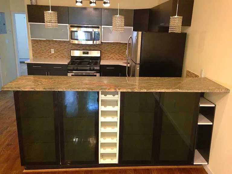 Kitchen features a large granite-topped island with seating space, plus stainless steel range, microwave, and fridge.