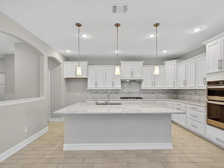 Kitchen featuring white shaker cabinetry, light-toned countertops, tile backsplash, stainless steel appliances, and recessed lighting