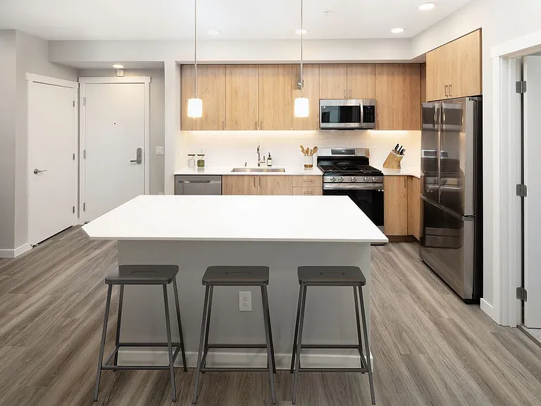 Kitchen with white quartz countertops, oak cabinetry, white subway tile backsplash, stainless steel appliances, and hard surface flooring