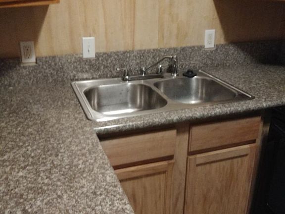 Kitchen with granite counters, hardwood cabinets, disposal, and ceramic tile floors.
