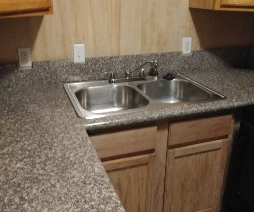 Kitchen with granite counters, hardwood cabinets, disposal, and ceramic tile floors.