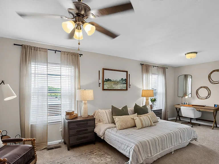 Inviting bedroom with warm lighting, chic decor, and a cozy workspace exuding comfort and style.
