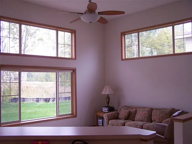 Main floor living space view from kitchen center island. Showcasing 12.5' ceiling and lots of natural light from windows