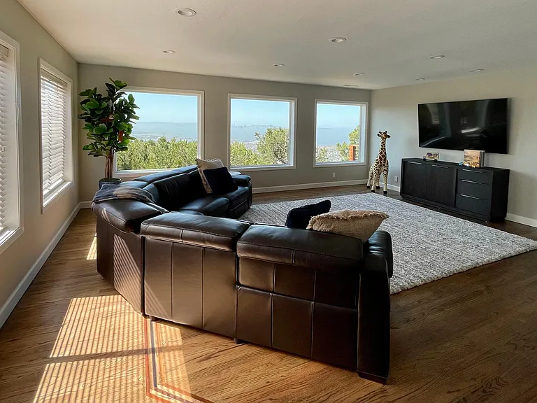 Family room with TV on wall and soft rug. We pull out mats and exercise here with weights stored in cabinet under the TV.