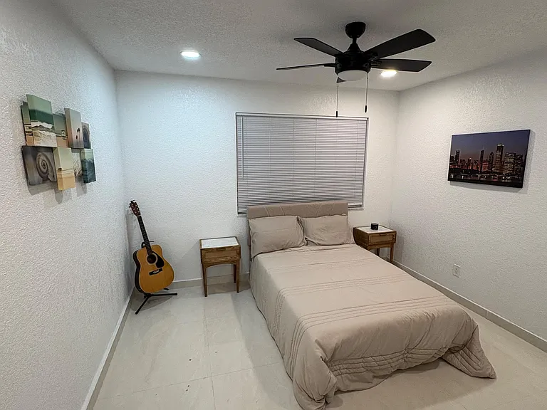 Well-kept bedroom with a comfortable bed, ceiling fan, and bedside tables, plus a window with blinds for privacy.
