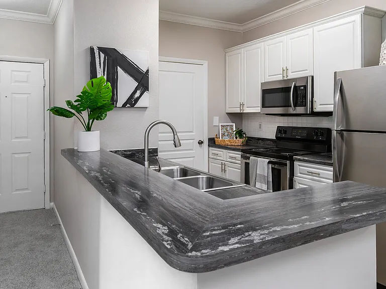 Whip up your favorite meals in this sleek kitchen, featuring stainless-steel appliances, modern white cabinetry, and a convenient breakfast bar perfect for casual dining.