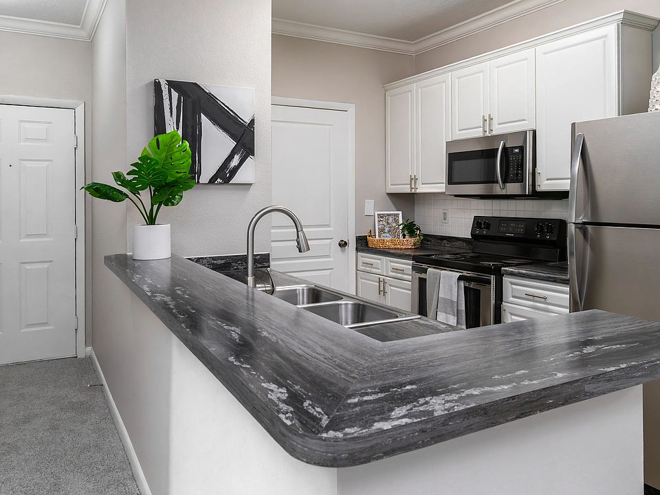 Whip up your favorite meals in this sleek kitchen, featuring stainless-steel appliances, modern white cabinetry, and a convenient breakfast bar perfect for casual dining.