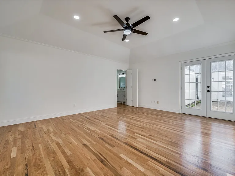 French doors lead from primary bedroom to courtyard area