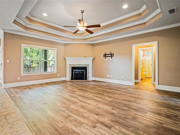 Unfurnished living room featuring crown molding, light hardwood / wood-style flooring, a fireplace, and ceiling fan