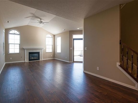 Great room with brand new laminate flooring, cathedral ceiling with ceiling fan and centered fireplace that is flanked by arched windows. Transom widow over entry door.