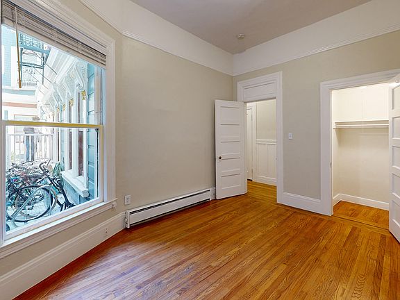 Bedroom with wood-like flooring, large window, and closet