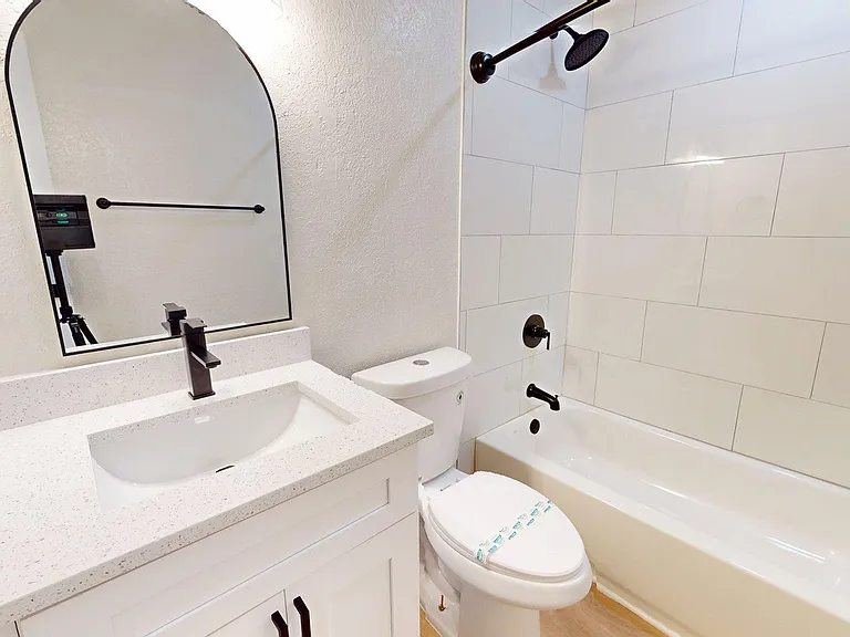 Elegant bathroom featuring a sleek vanity with white countertop, modern fixtures, and a pristine bathtub with tiled wall. Elegant bathroom featuring a sleek vanity with white countertop, modern fixtures, and a pristine bathtub with tiled wall.