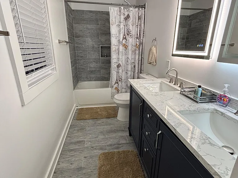 Room 1 Full bathroom with double sink, vanity with stone-look countertop, and an LED-lit mirror for daily routines.