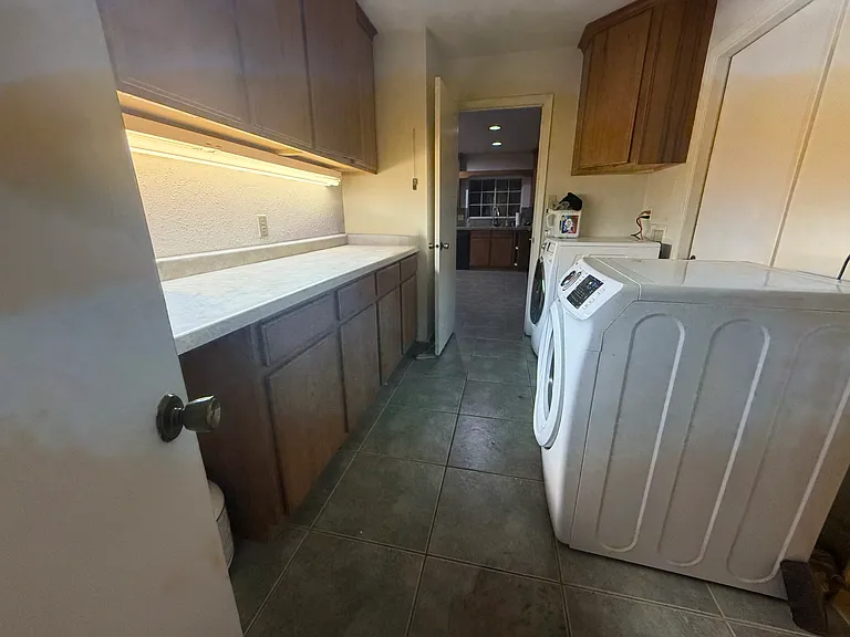 A spacious laundry and craft room with dual entrances offers exceptional functionality and organization, featuring additional built-in storage and plenty of workspace. The washer and dryer are included for added convenience.