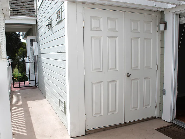 Walkway from back patio to front entrance and doors to outdoor storage