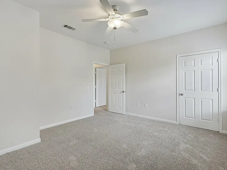 Bright and airy bedroom with plush carpeting and modern ceiling fan, featuring white walls and ample natural light. Bright and airy bedroom with plush carpeting and modern ceiling fan, featuring white walls and ample natural light.