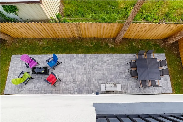 Overlooking the backyard patio from the rooftop balcony. Enclosed backyard space contains outdoor dining for 8, propane grill, and 4 Adirondak chairs around a firepit.