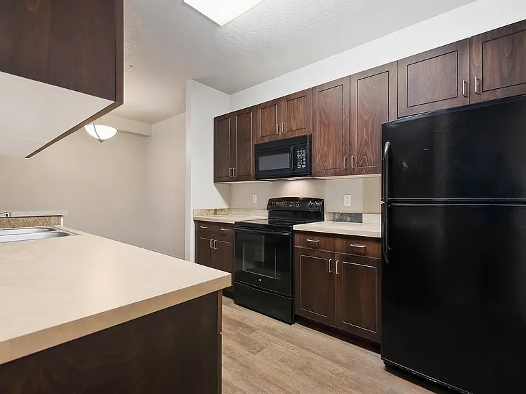 Feel at home setting; spacious cabinetry with black appliances and stainless-steel sink; with natural lighting streaming through, the space feels bright and inviting, making it the heart of your home