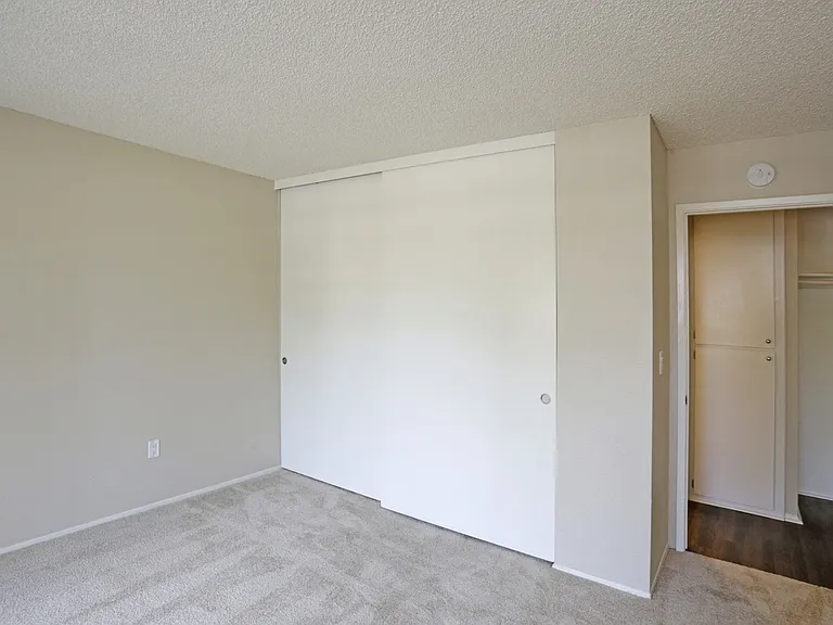 Carpeted bedroom with large closet at Villa Pacific Apartments in Oceanside, California.