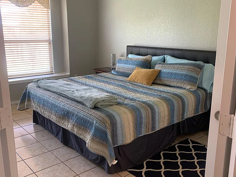 Entry to the first floor Master bedroom with King size bed, fully tiled floors, crown molding, and ceiling fan.