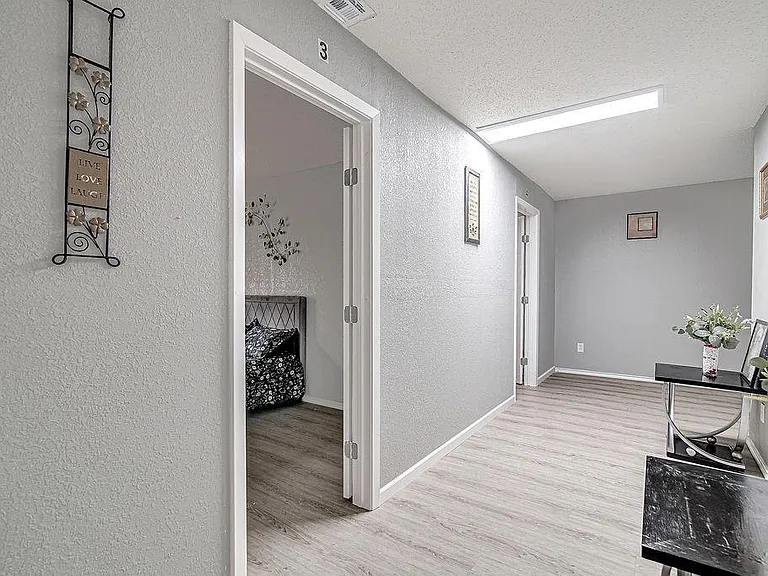 Wide hallway with durable wood-look flooring, overhead lighting, and access to multiple rooms for easy circulation.