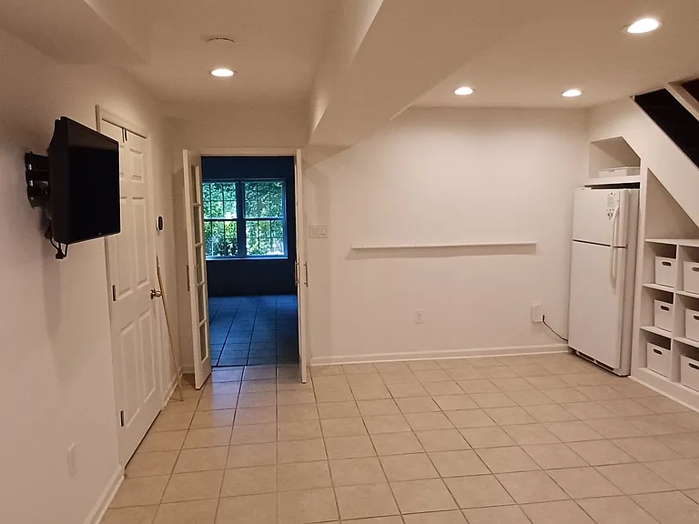 Basement family/rec room with TV and full refrigerator. Laundry, storage and utility rooms to left.