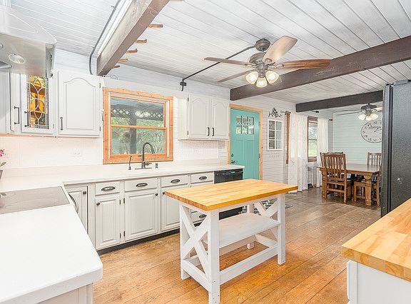 White washed wood ceiling with wood beams bring the charm in to the kitchen. Wood planked floors and new light fixtures.