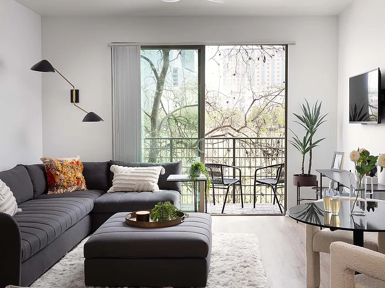 Apartment living room with wood-style flooring and balcony or patio in select homes.