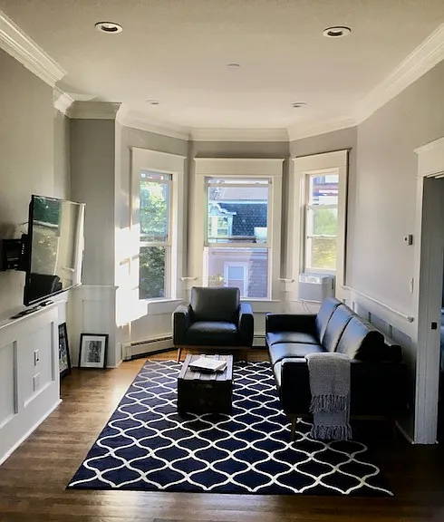 Bright living room with three bay windows and abundant natural light.