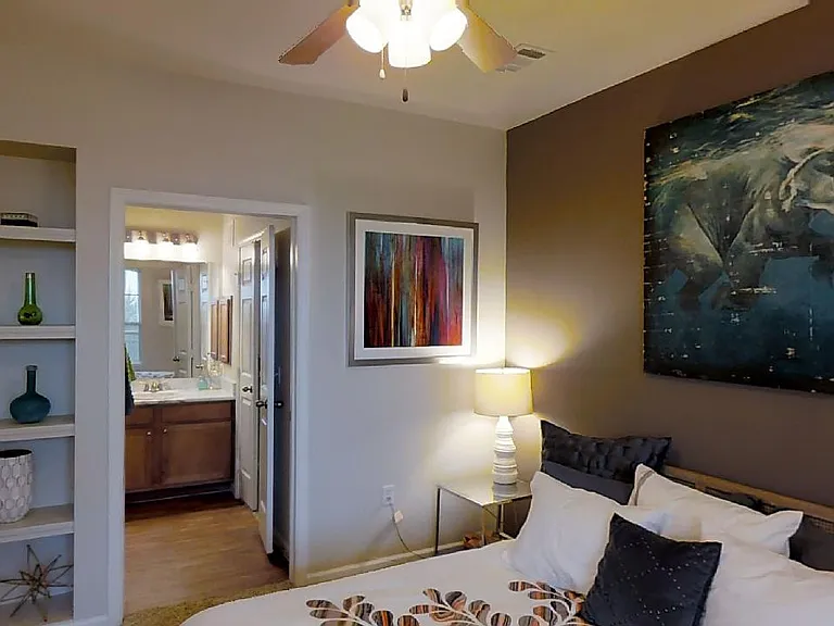 Spacious apartment bedroom with attached bathroom and plush carpet flooring.